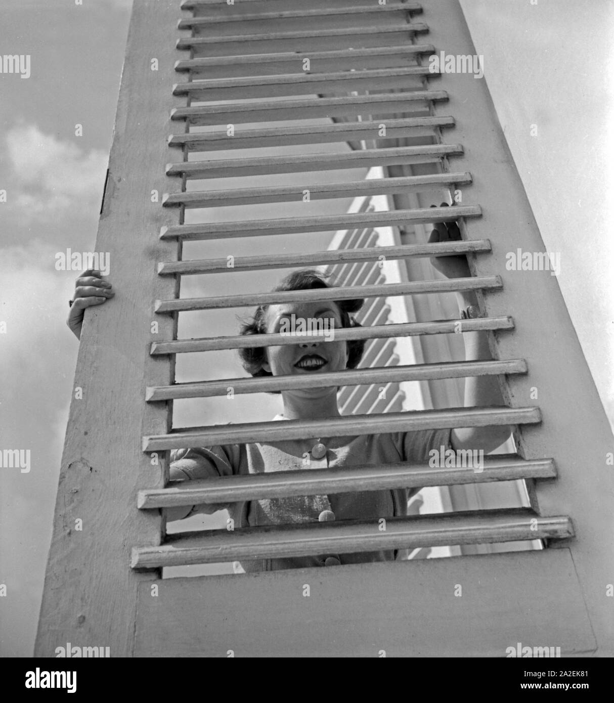 Eine Frau schaut durch die Fensterläden von Schloß Solitude in Stuttgart, Deutschland 1930er Jahre. A woman looking through a folding shutter of Solitude castle at Stuttgart, Germany 1930s. Stock Photo