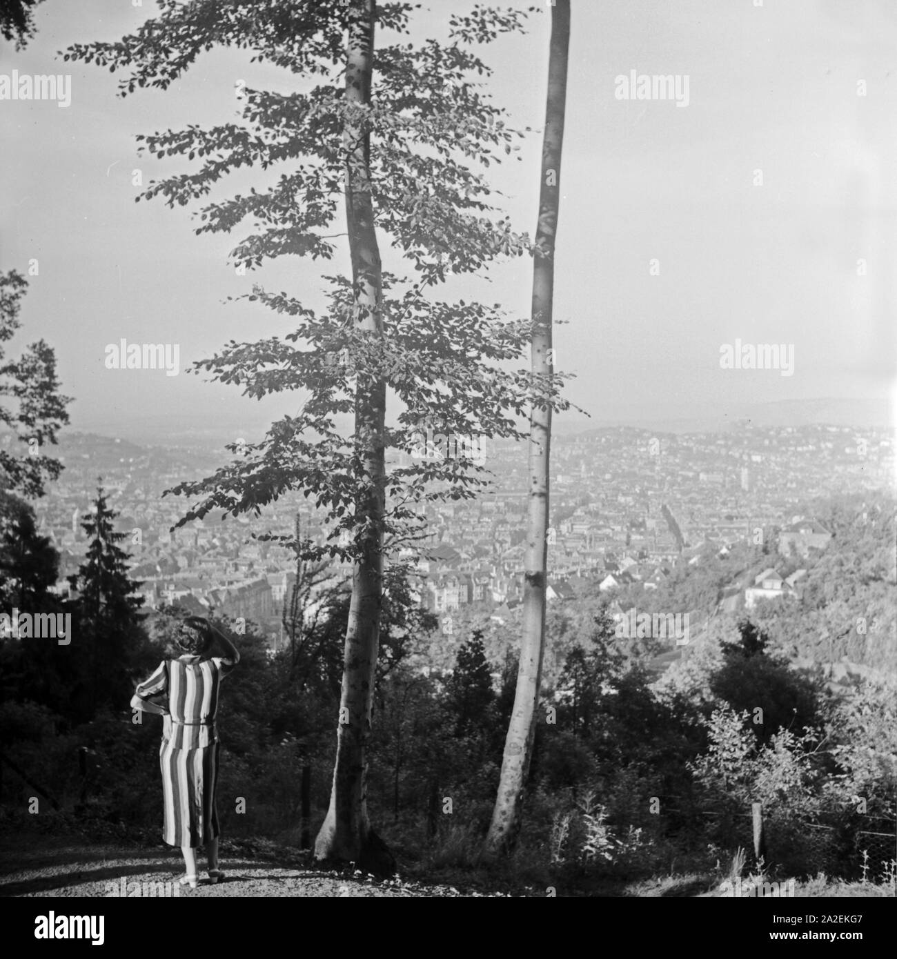 Eine Frau steht auf einer Anhöhe und blickt auf die Stadt Stuttgart, Deutschland 1930er Jahre. A woman standing on a hill and viewing the city of Stuttgart, Germany 1930s. Stock Photo