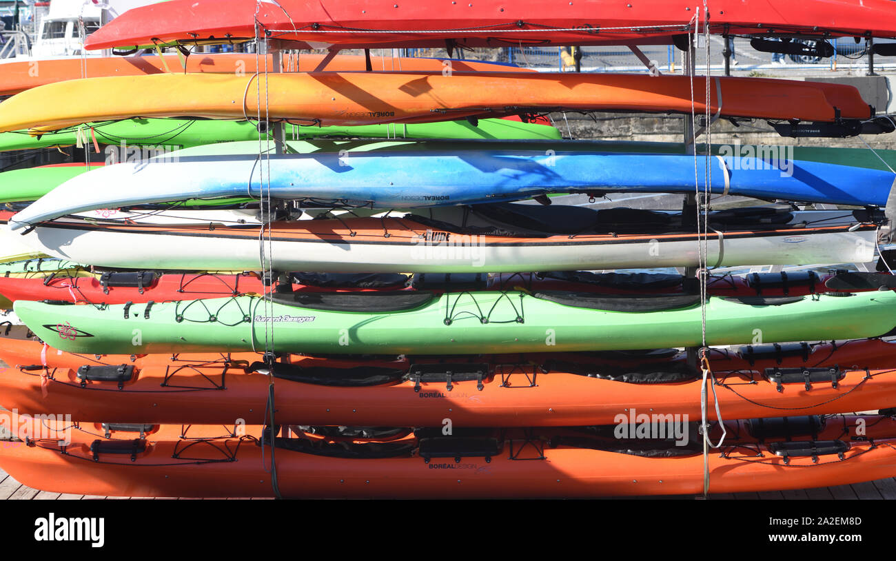 Multi-coloured kayaks for hire stacked up on the waterfront.  Victoria, British Columbia, Canada. Stock Photo