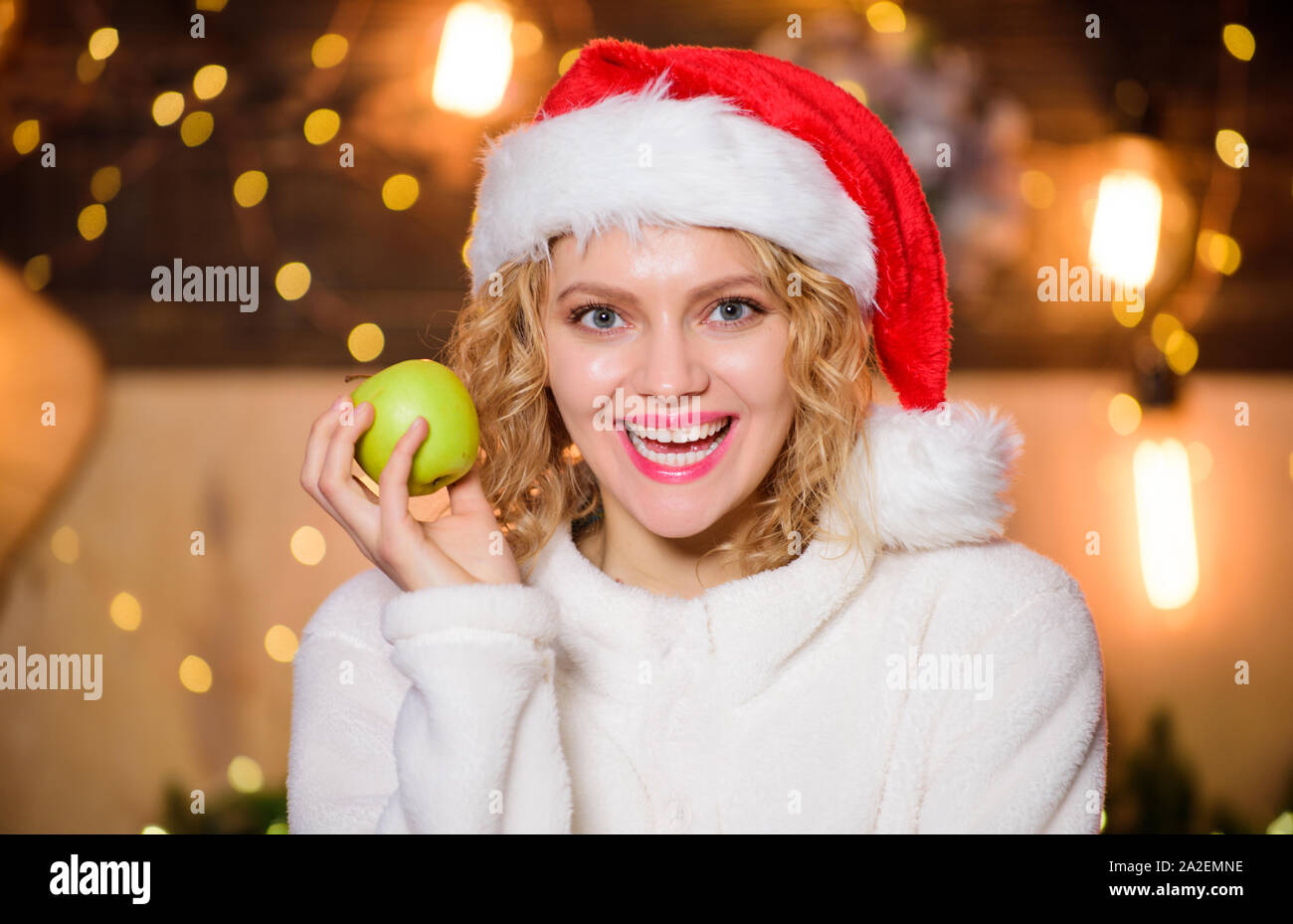 Health care. Woman Santa hat eat apple fruit christmas decorations