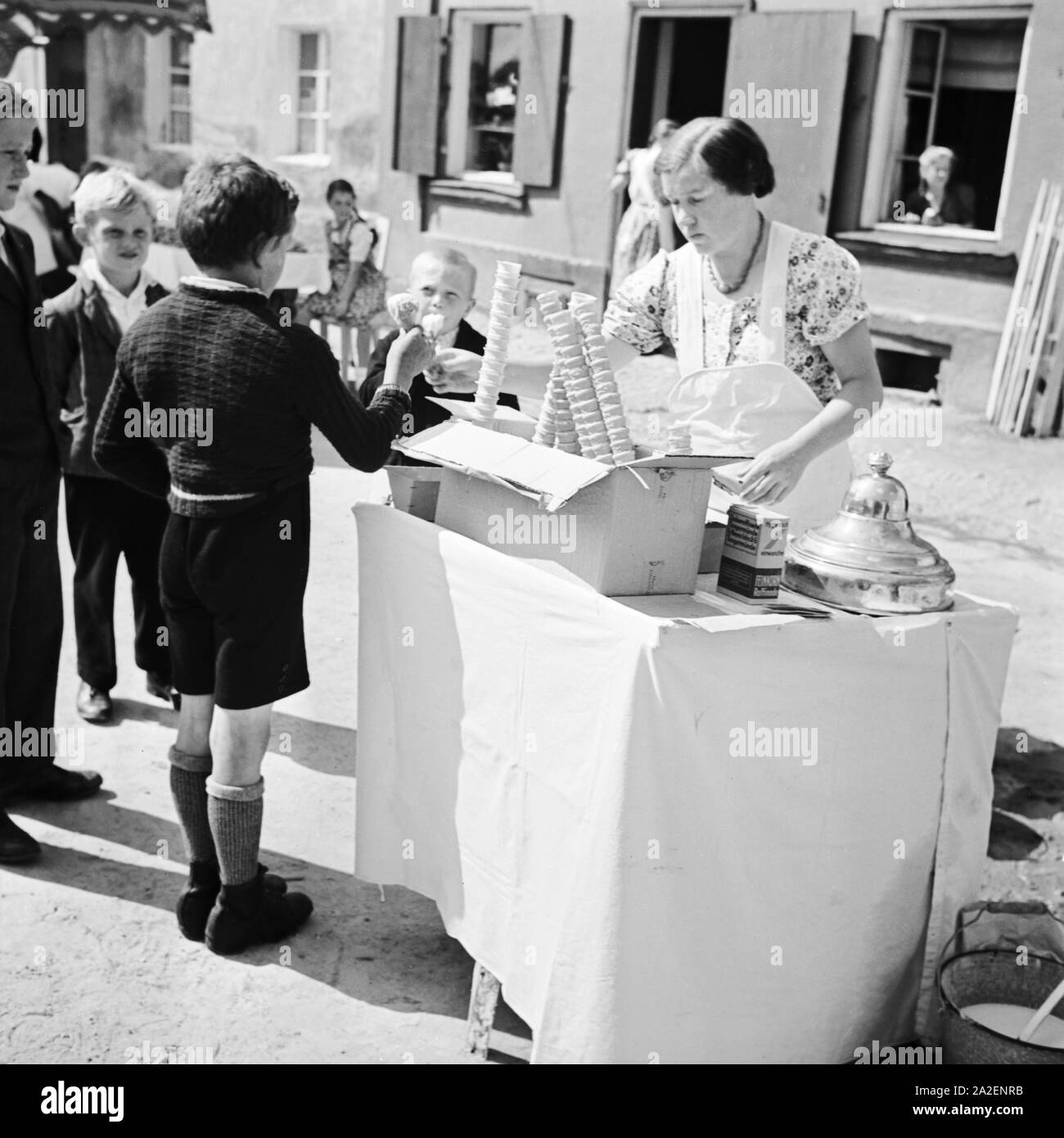 Kinder kaufen am Eisstand bei der Eisverkäuferin ein Eis, Deutschland 1930er Jahre. Children buying an icecream at an icecream booth, Germany 1930s. Stock Photo