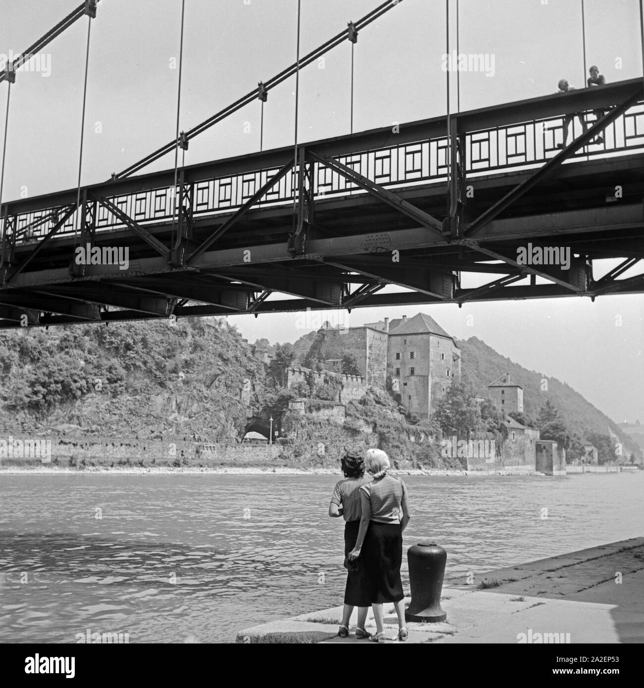 Zwei Jungen winken zwei Frauen von einer Brücke über die Donau bei Passau zu, Deutschland 1930er Jahre. Two boys cheering to two young women from a bridge over river Danube at Passau, Germany 1930s. Stock Photo