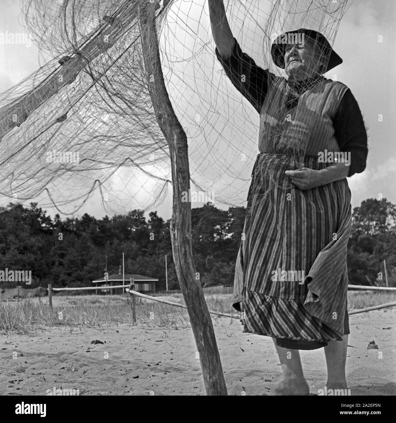 Eine Fischerin bei Rositten an der Ostsee sortiert seine Netze, Ostpreußen, Deutschland 1930er Jahre. A fisherwoman assorting his net at Rositten on the Baltic Sea in East Prussia, Germany 1930s. Stock Photo