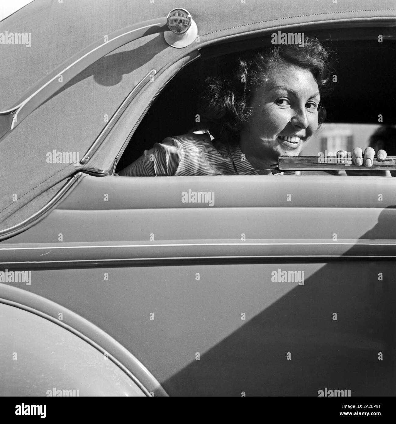 Eine junge Frau schaut aus dem Fenster eines abgedeckten Cabrio Ford V8, Deutschland 1930er Jahre. A young female looking out of the window of a closed convertible Ford V8, Germany 1930s. Stock Photo