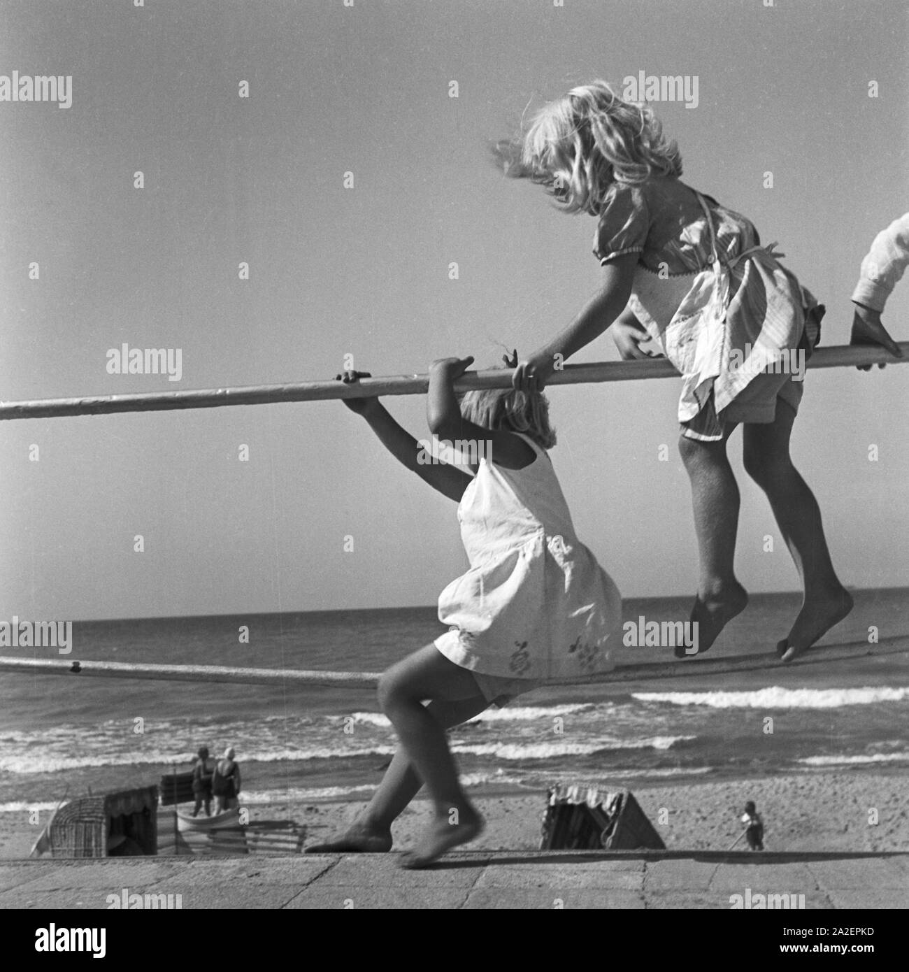 Zwei kleine Kinder turnen an einem Geländer an der Ostsee in Ostpreußen, Deutschland 1930er Jahre. Two little girls playing at a railing at the shore of the Baltic Sea in East Prussia, Germany 1930s. Stock Photo