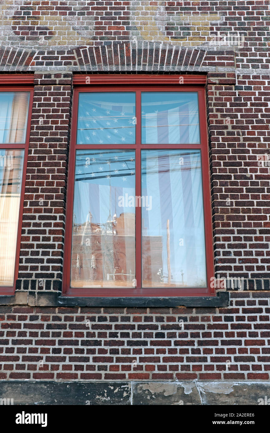 A US flag in the window of a brick building. Stock Photo