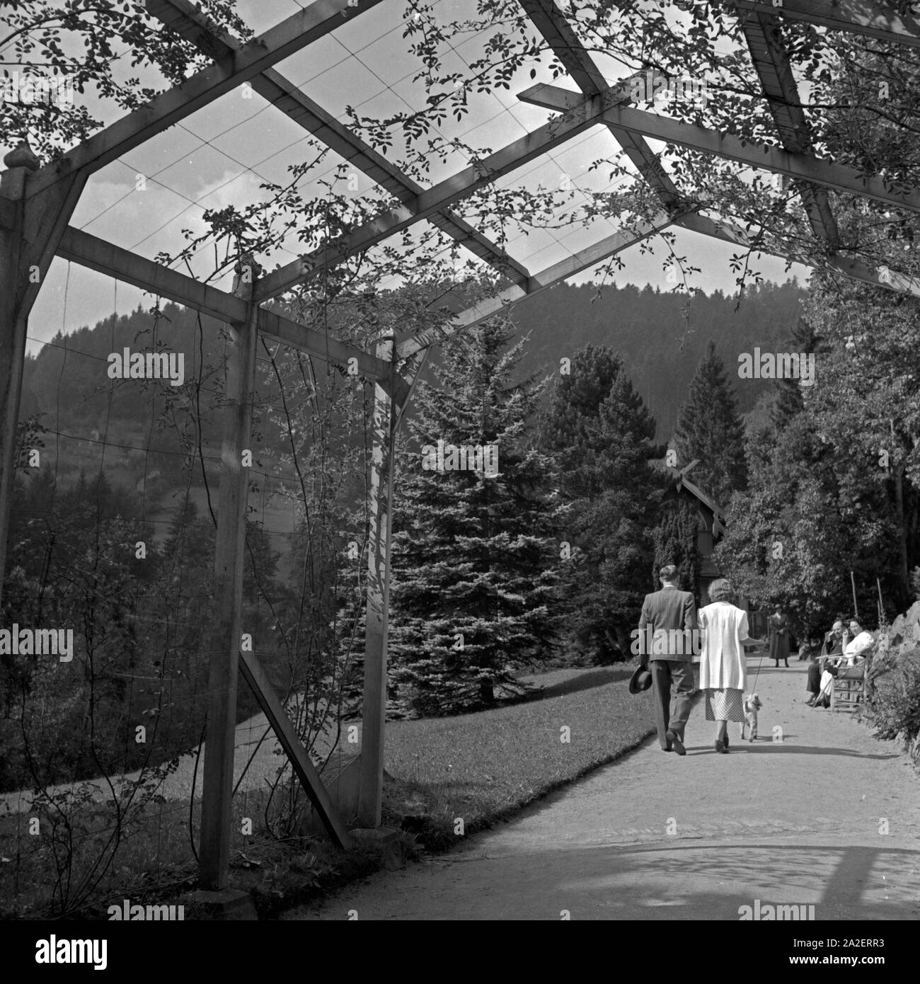 Ein Paar kommt bei einem Spaziergang aus einem Laubengang in Wildbad im Schwarzwald, Deutschland 1930er Jahre. A couple strolling through an access balcony at Wildbad in Black Forest, Germany 1930s. Stock Photo