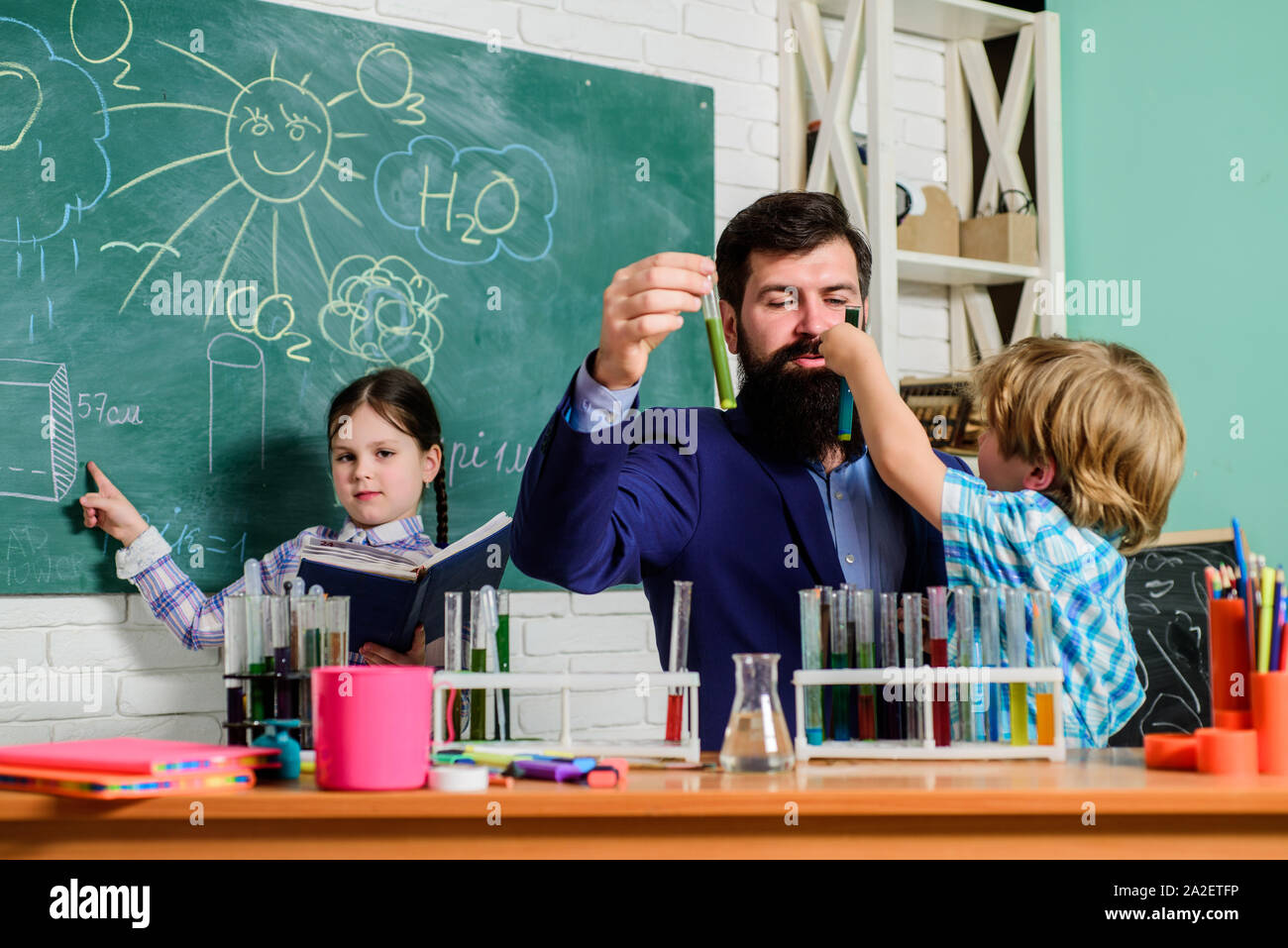 School clubs interactive education. Clubs for preschoolers. After school clubs are great way to develop kids in different areas. Chemistry experiment. Teacher and pupils test tubes in classroom. Stock Photo