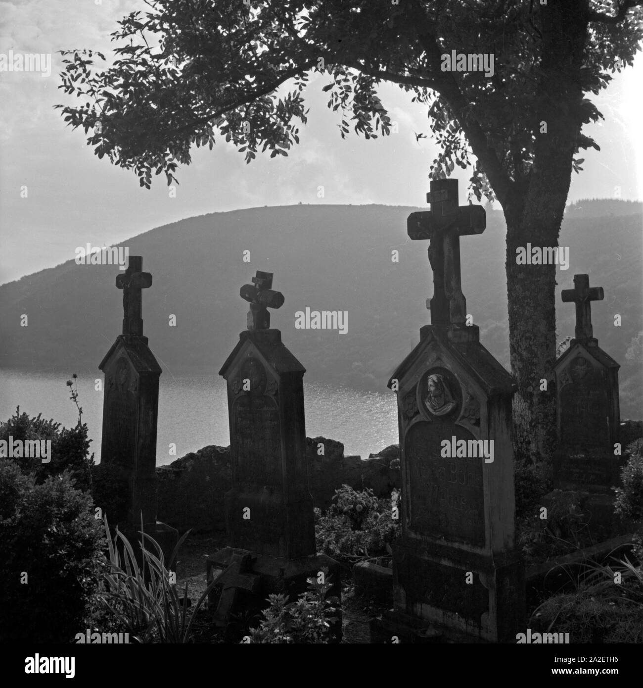 Grabkreuze auf dem Friedhof mit Blick auf das Totenmaar in Weinfeld bei Daun in der Eifel, Deutschland 1930er Jahre. Tombstones with view to Totenmaar maar lake at Weinfeld near Daun at Eifel region, Germany 1930s. Stock Photo