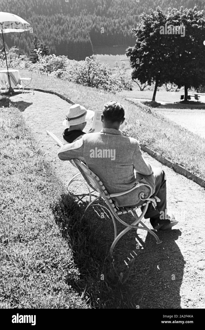 Ein junges Paar entspannt bei der Zeitschriftenlektüre im Garten, Freudenstadt, Deutschland 1930er Jahre. A young couple relaxing with a magazine in the garden, Freudenstadt, Germany 1930s. Stock Photo