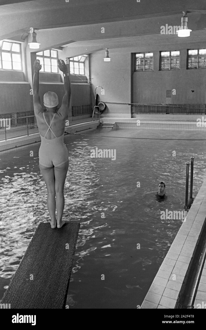 Junge Frau auf dem Sprungturm im Schwimmbad, Freudenstadt, Deutschland 1930er Jahre. Young woman standing on the diving tower in a swimming pool, Freudenstadt, Germany 1930s. Stock Photo