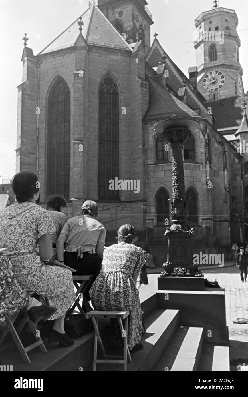 Junge Frauen vor der Stiftskirche sitzend, Stuttgart, Deutschland 1930er Jahre. Young women sitting in front of the Stiftskirche (Collegiate Church)  in Stuttgart, Germany 1930s. Stock Photo