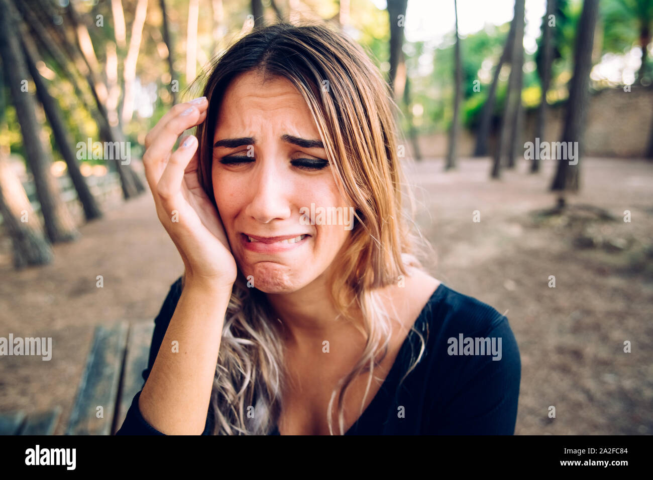 Beautiful woman's face sobbing in disgust as she rests her head on her hand. Stock Photo