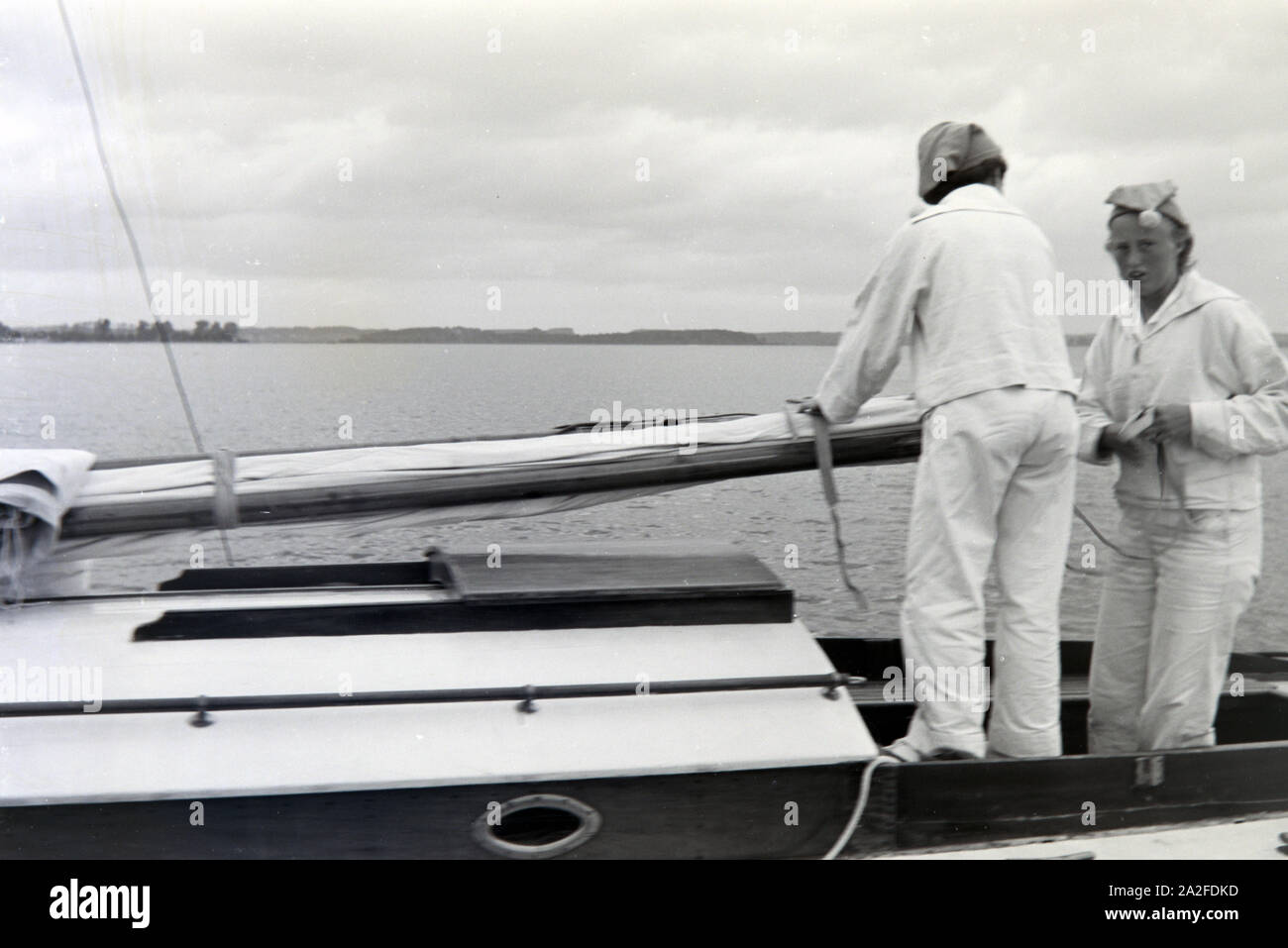 Zwei Seglerinnen in Seglerbekleidung mit Bommelmütze auf einem Bootsausflug auf dem Chiemsee, Deutschland 1930er Jahre. Two yachtswomen in a sailing uniform on a boat on the Chiemsee, Germany 1930s. Stock Photo