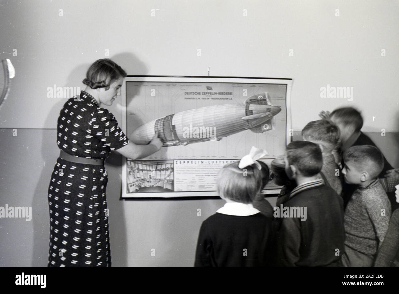 Eine Schulklasse lässt sich mit großem Interesse von ihrer Lehrerin den Aufbau eines Zeppelins erklären, Zeppelin Siedlung bei Frankfurt am Main, Deutschland 1930er. A teacher is explaining the construction of a zeppelinl to her pupils who are listening with great interest, zeppelin village near Frankfurt am Main, Germany 1930s. Stock Photo