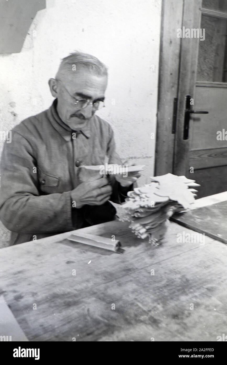 Ein Mitarbeiter in den Heller Kunst Werkstätten in der Eifel schleift die Kanten der ausgesägten Holzfiguren ab, Deutschland 1930er Jahre. An employee of the Heller Kunst workshops in the Eifel grinding the edges of the sawn out wooden figures, Germany 1930s. Stock Photo