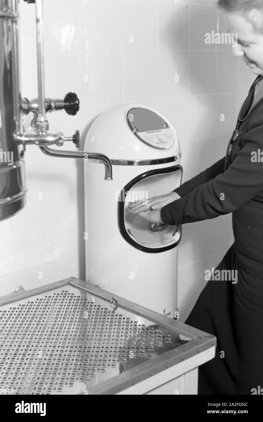 Eine Frau testet einen automatischen Händetrockner, Deutschland 1930er Jahre. A woman is testing an automatic hand dryer, Germany 1930s. Stock Photo