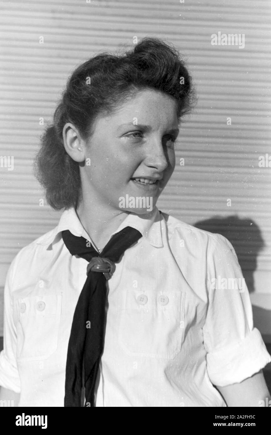 Porträt eines BDM Mädchens in Uniform mit der weißen Bluse, schwarzem  Halstuch und Lederknoten, Deutschland 1930er Jahre. Portrait of a uniformed  BDM girl wearing the white blouse, black neckerchief and leather slide,
