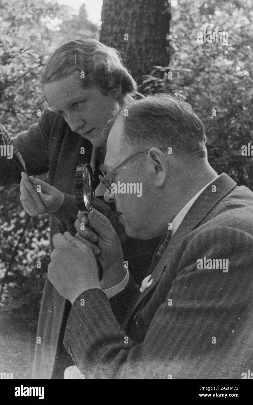 Ein Mann und eine Frau prüfen einen Schmalfilm, Deutschland 1930er Jahre. A man and a woman checking a substandard film, Germany 1930s. Stock Photo