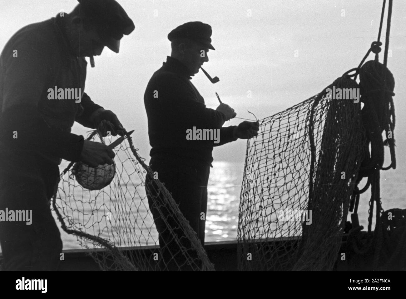 Hochseefischer bereiten die Netze vor, Deutschland 1930er Jahre. Deep sea fishermen preparing the net, Germany 1930s. Stock Photo