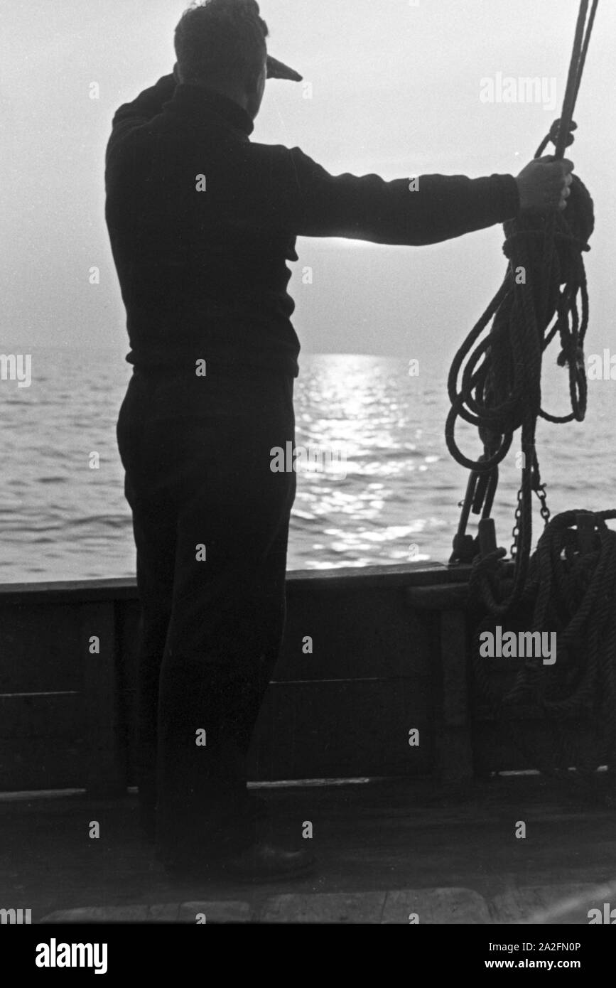 Ein Hochseefischer beobachtet die See, Deutschland 1930er Jahre. Deep sea fisherman checking the sea, Germany 1930s. Stock Photo