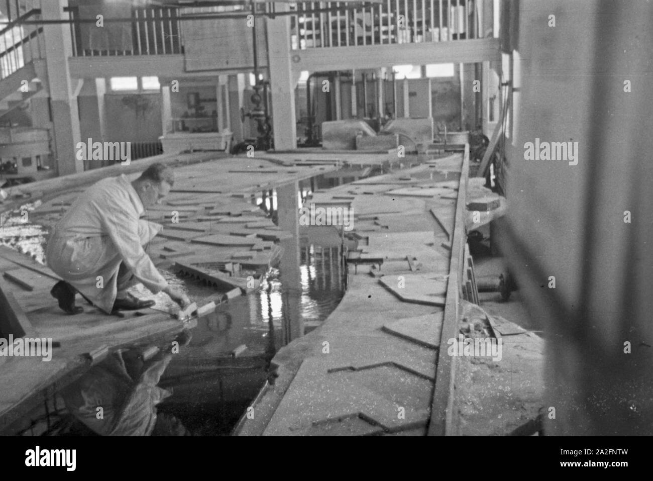 Im Flußbau Laboratorium in Karlsruhe wird ein Modell eines Staudamms durch einen Modellbauer modelliert, Deutschland 1930er Jahre. At the river engineering laboratory at Karlsruhe a model of a river barrage is constructed by a model maker, Germany 1930s. Stock Photo