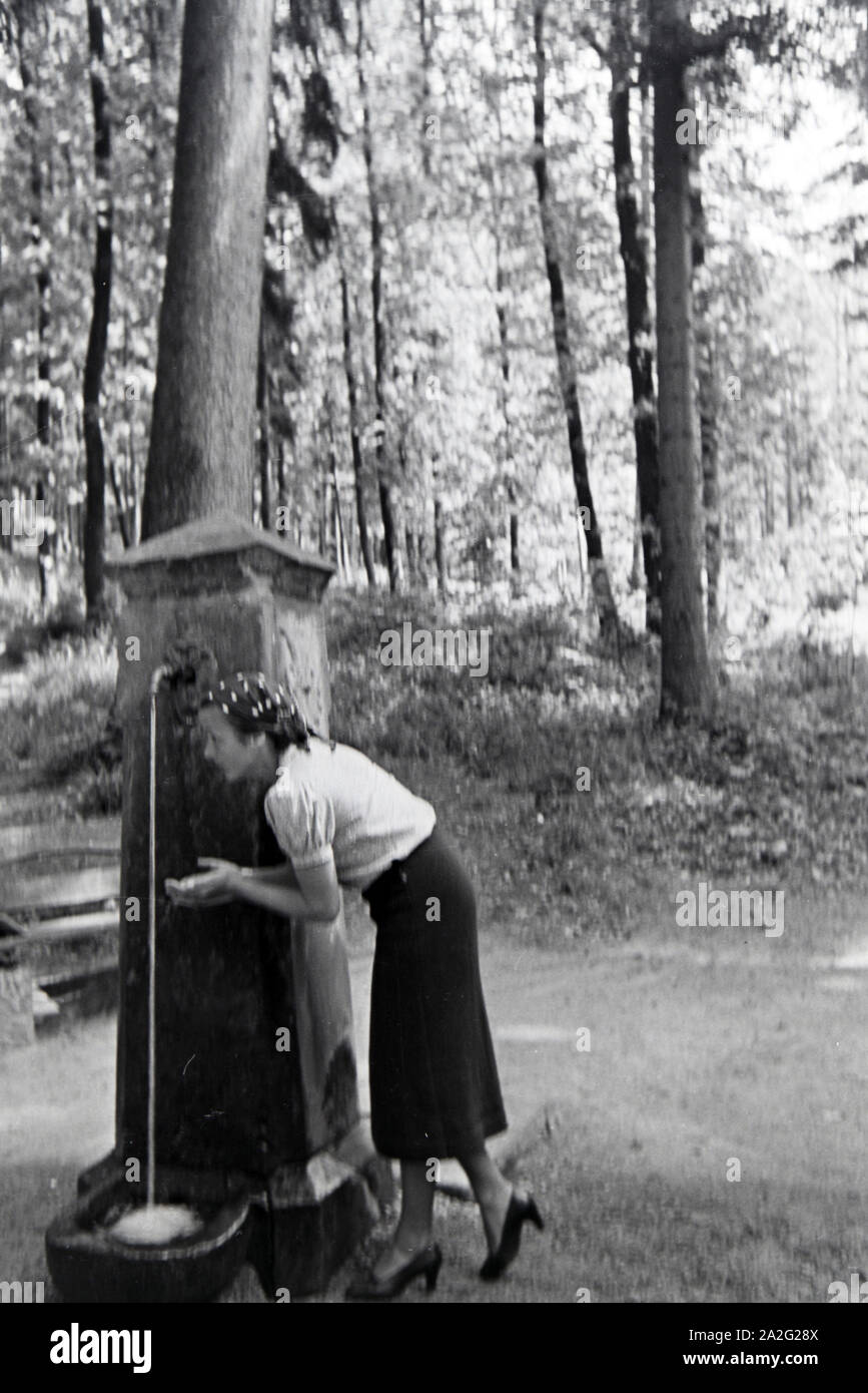 Eine junge Frau probiert das Trinkwasser des Eberbrunnens auf einem Wanderpfad bei Baden-Baden im Nordschwarzwald, Deutschland 1930er Jahre. A young w Stock Photo