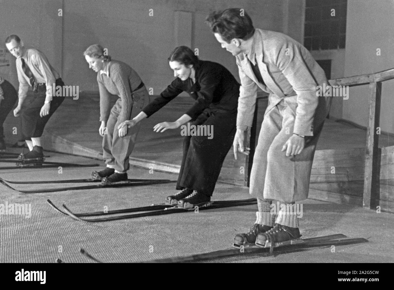 Ein Skilehrer beim Unterricht mit Ski Anfängern in einer Skihalle, Deutschland 1930er Jahre. A skiing teacher at a lesson with skiing beginners, Germany 1930s. Stock Photo