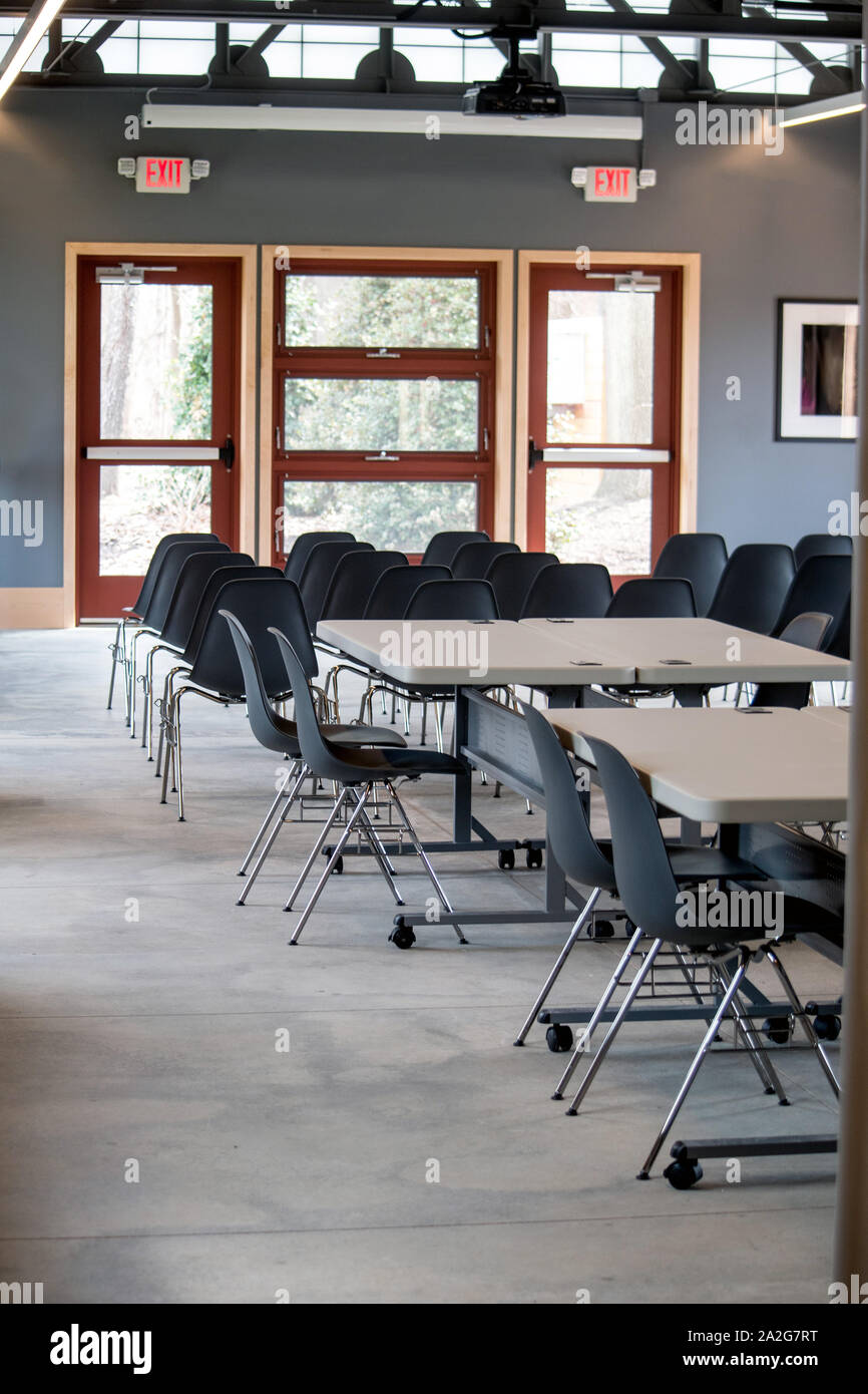 A large conference room is ready for the next group of people, with tables and chairs set up for a crowd Stock Photo