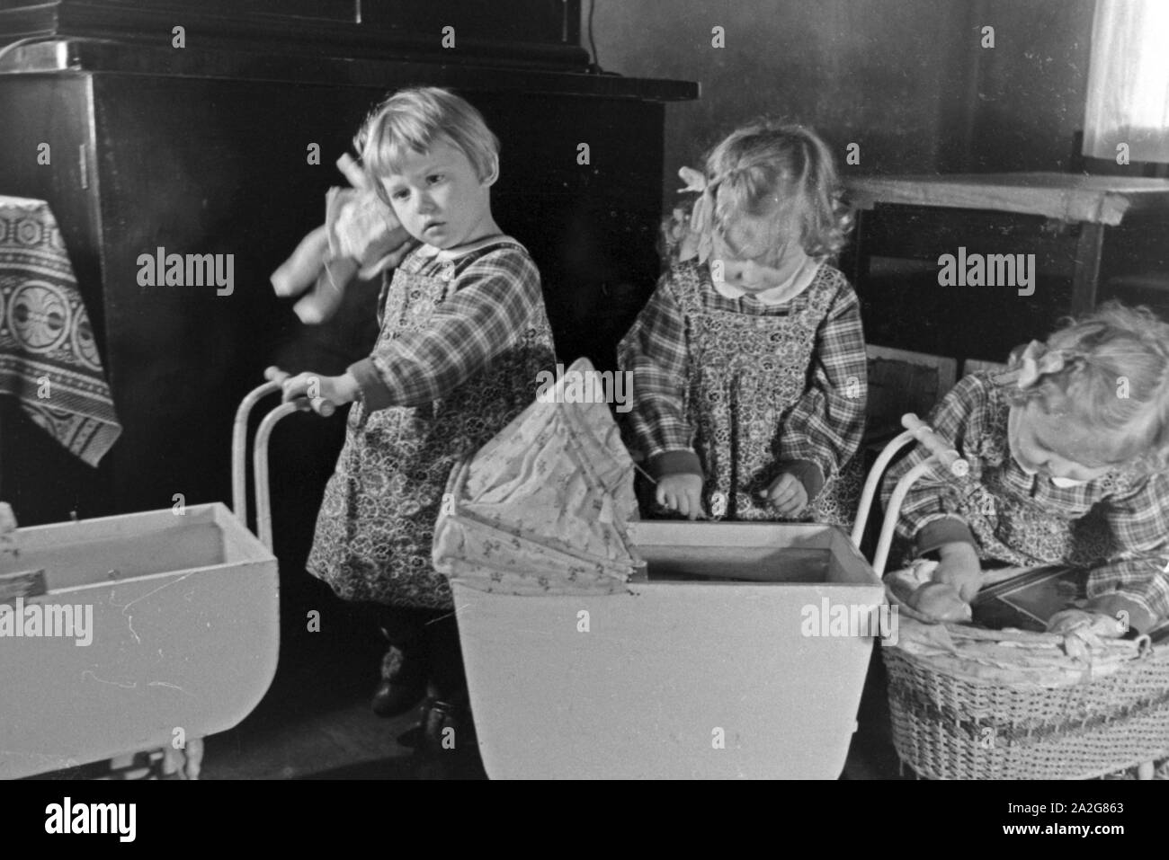 Drei der Knipser Vierlinge als Kleinkinder mit ihren Puppenwagen, Deutschland 1930er Jahre. Three of Knipser's quadruplet girls with their doll's prams, Germany 1930s. Stock Photo