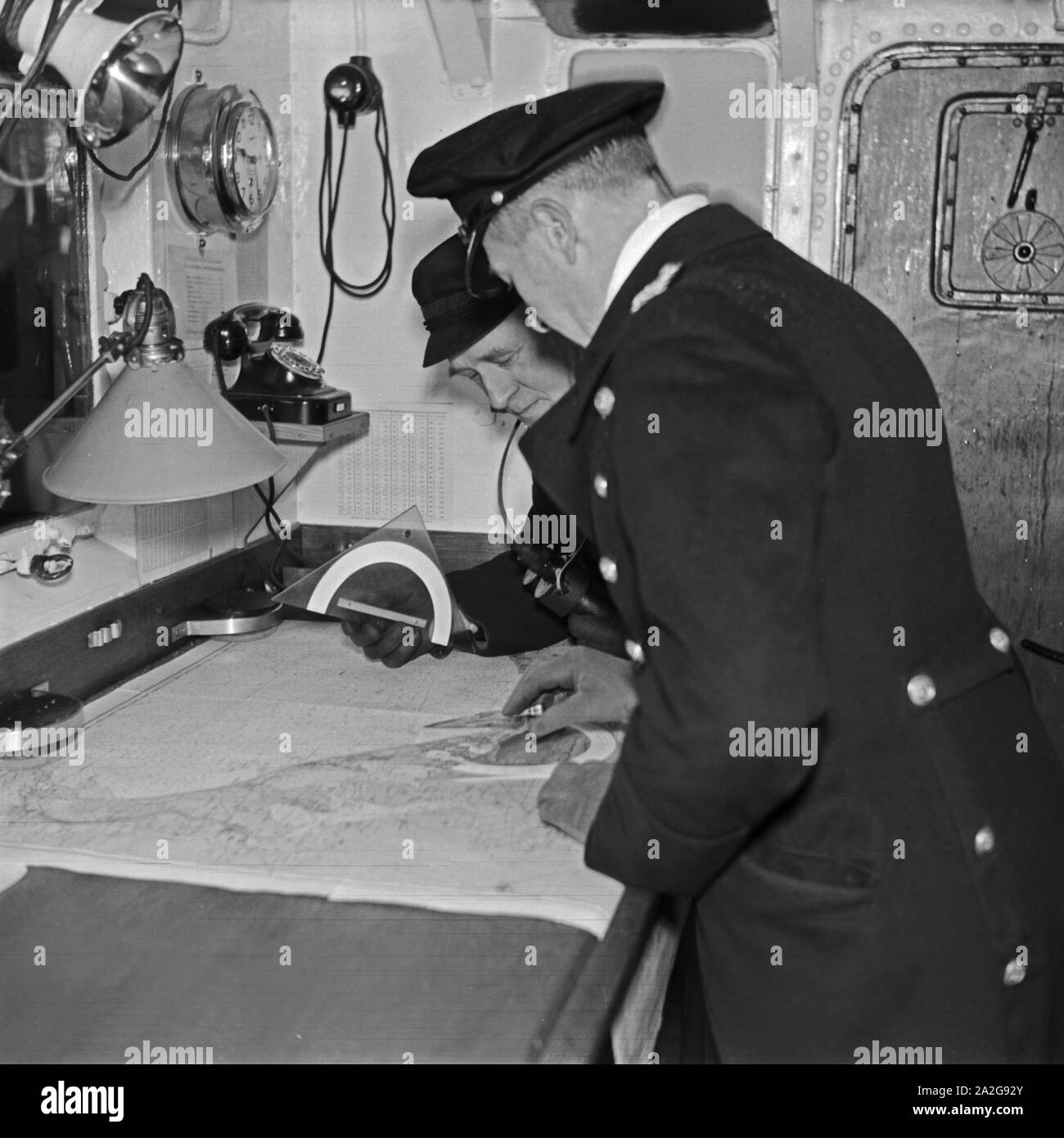 Offizier und Bootsmann bei der Navigation auf einem Minensuchboot, Deutschland 1930er Jahre. Officer and petty officer navigating a minesweeper, Germany 1930s. Stock Photo