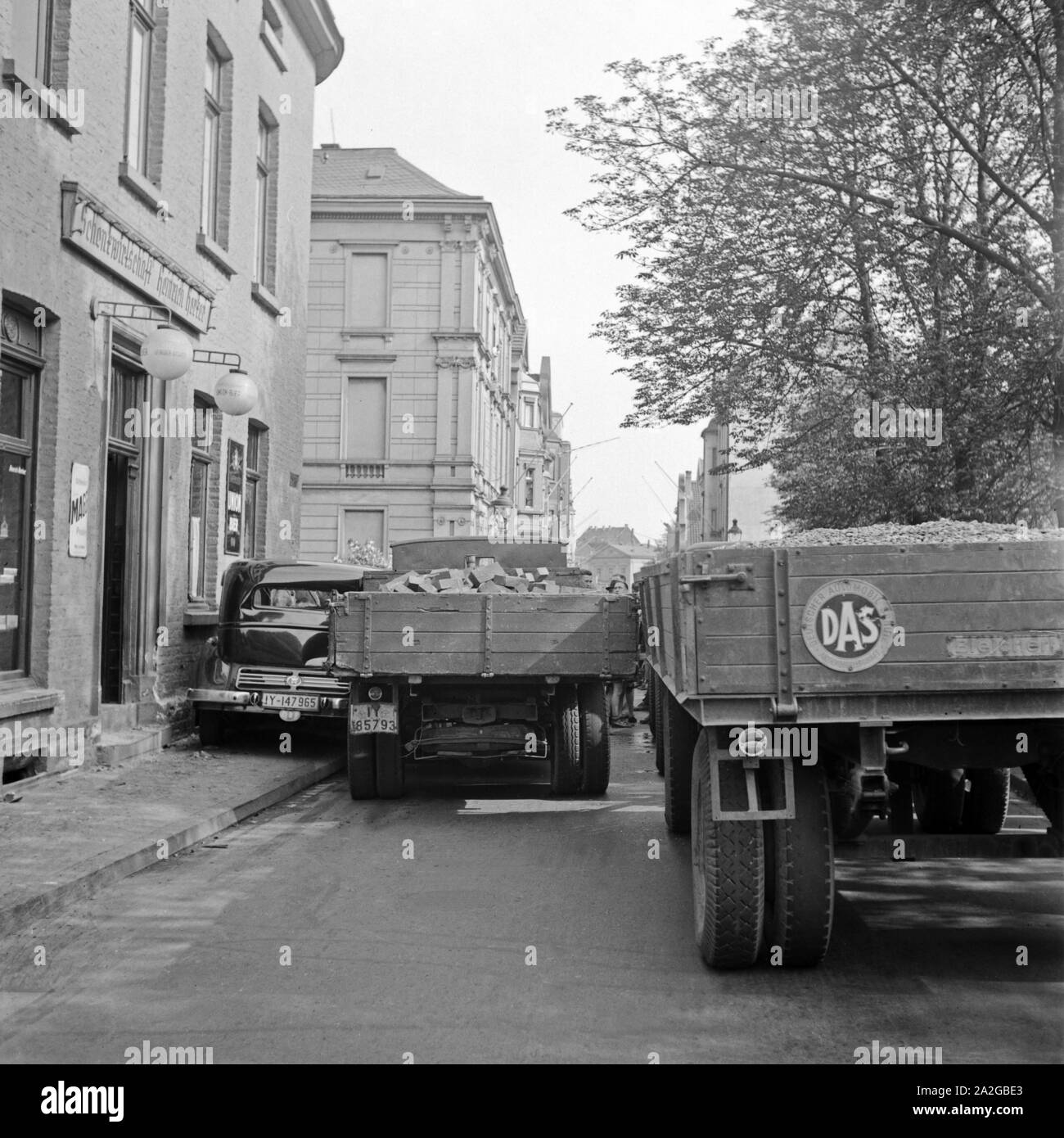 Lastkraftwagen rangieren durch eine Straße vor der Schankwirtschaft Herker in Krefeld, Deutschland 1930er Jahre. Vans shunting in a street in front of the Herker pub at Krefeld, Germany 1930s. Stock Photo