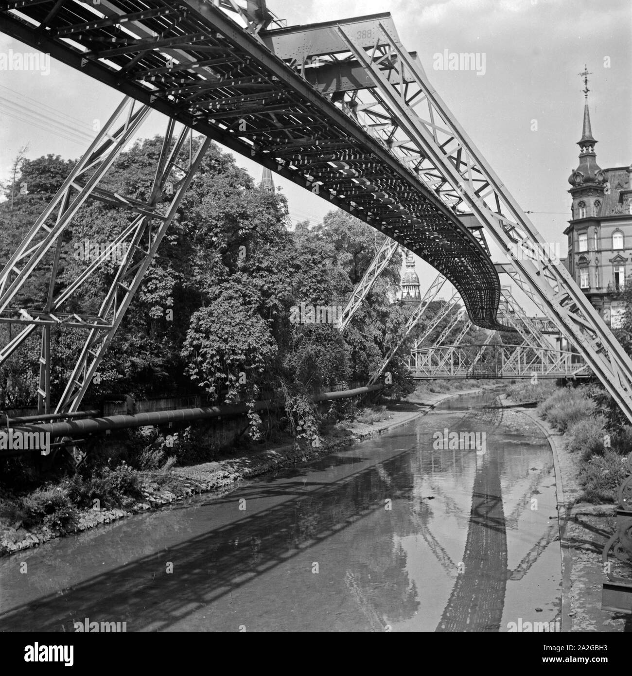 Die Strecke der Wuppertaler Schwebebahn spiegelt sich in der Wupper, Deutschland 1930er Jahre. Wuppertal Suspension Railway refelcting in the river Wupper, Germany 1930s. Stock Photo