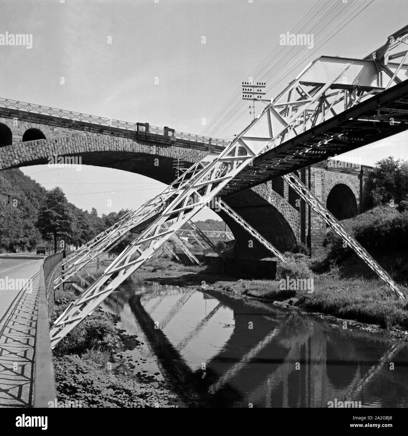 Die Strecke der Wuppertaler Schwebebahn spiegelt sich in der Wupper in Elberfeld, Deutschland 1930er Jahre. Wuppertal Suspension Railway refelcting in the river Wupper, Germany 1930s. Stock Photo
