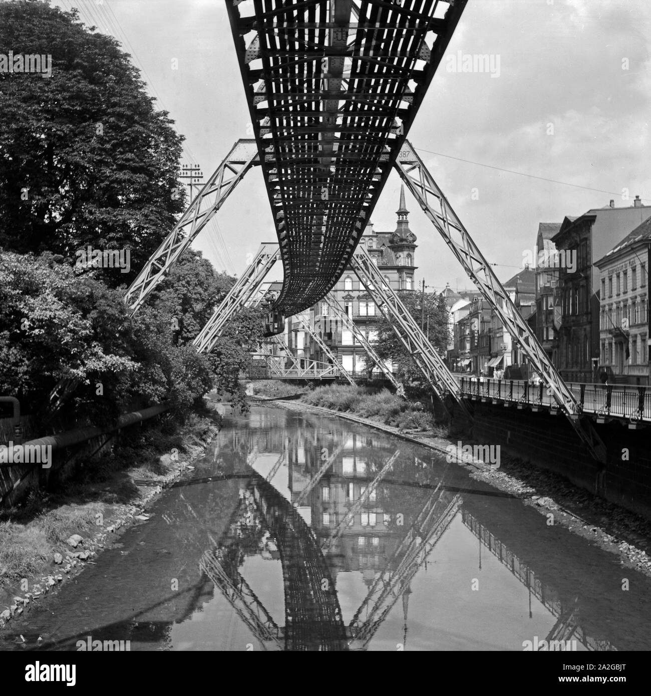 Die Strecke der Wuppertaler Schwebebahn spiegelt sich in der Wupper, Deutschland 1930er Jahre. Wuppertal Suspension Railway refelcting in the river Wupper, Germany 1930s. Stock Photo