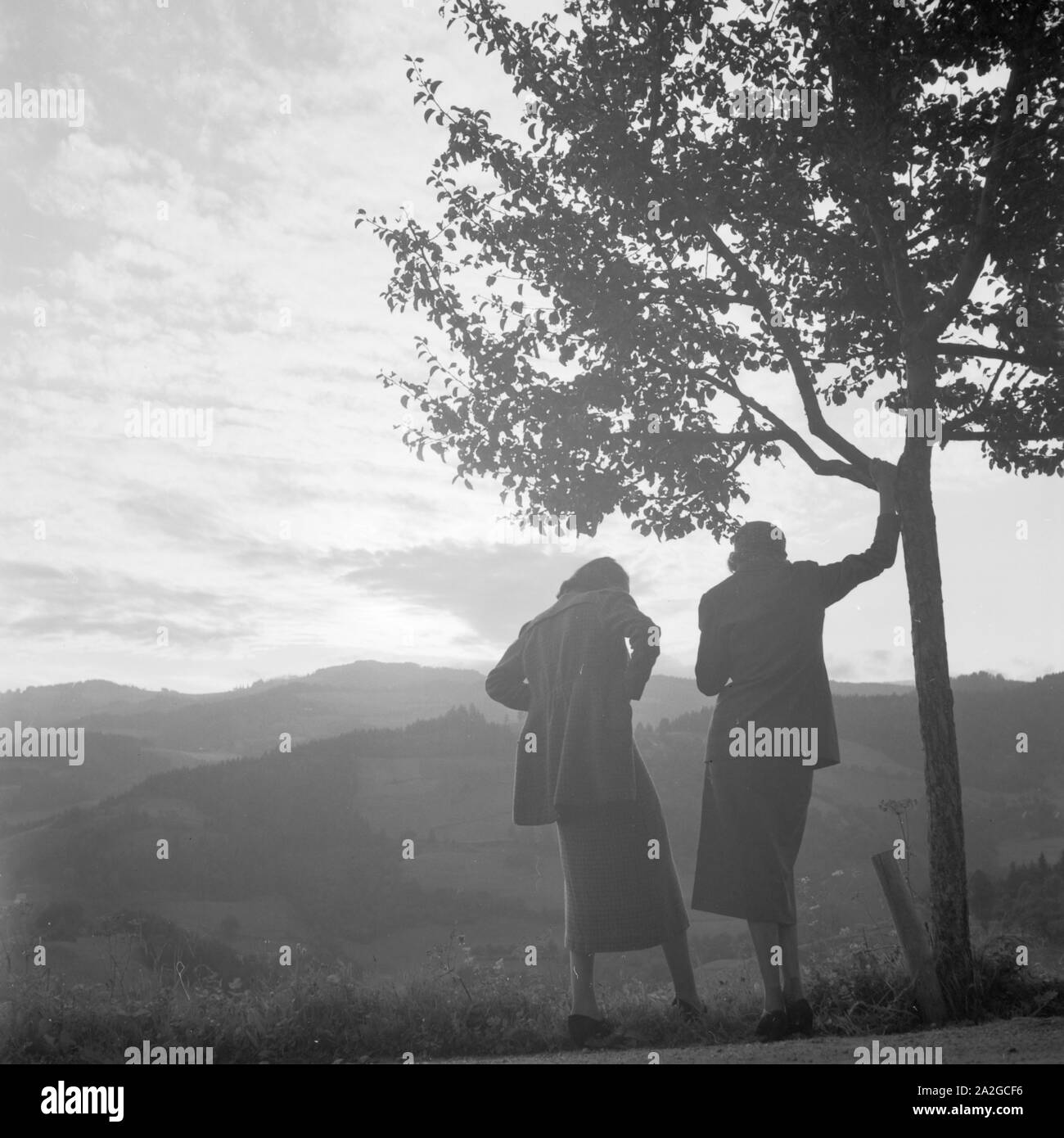 Zwei Frauen an einem Baum im Gegenlicht, Deutschland 1930er Jahre. Two women standing by a tree