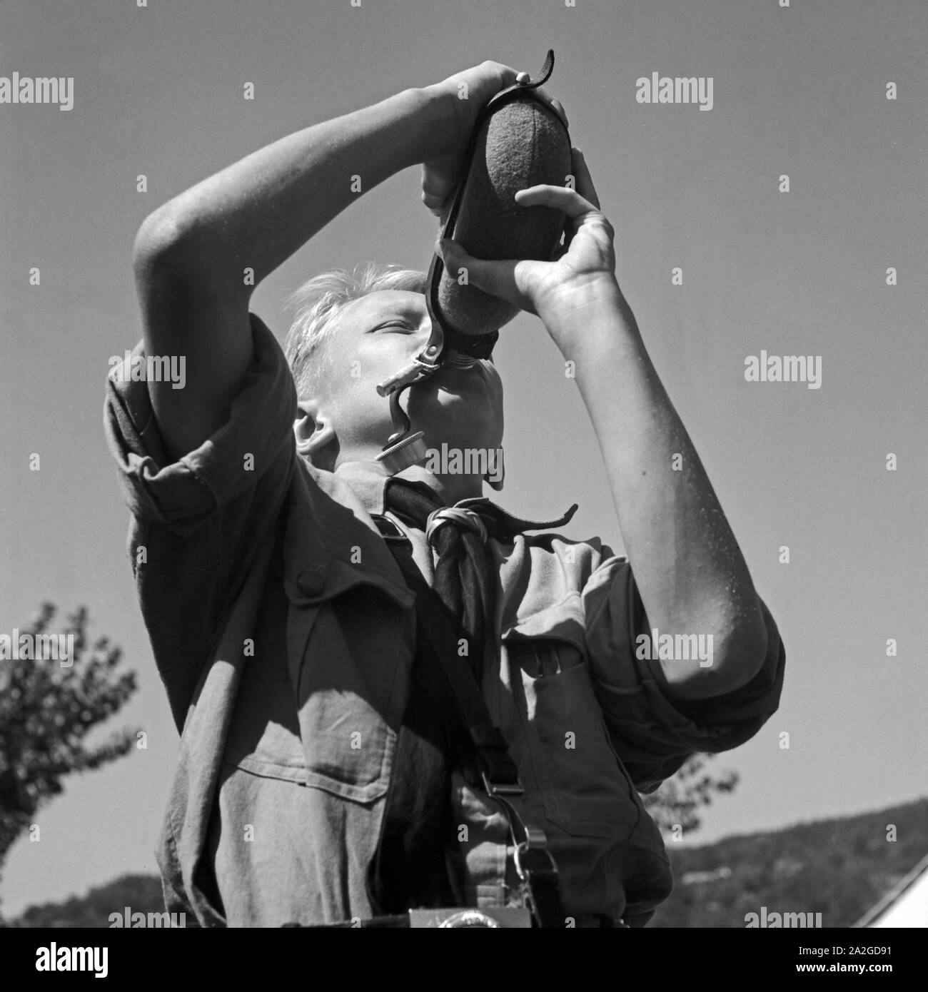 Durstiger Hitlerjunge trinkt aus seiner Feldflasche im Hitlerjugend Lager, Österreich 1930er Jahre. Thirsty Hitle youth dirnking from his water bottle at the Hitler youth camp, Austria 1930s. Stock Photo