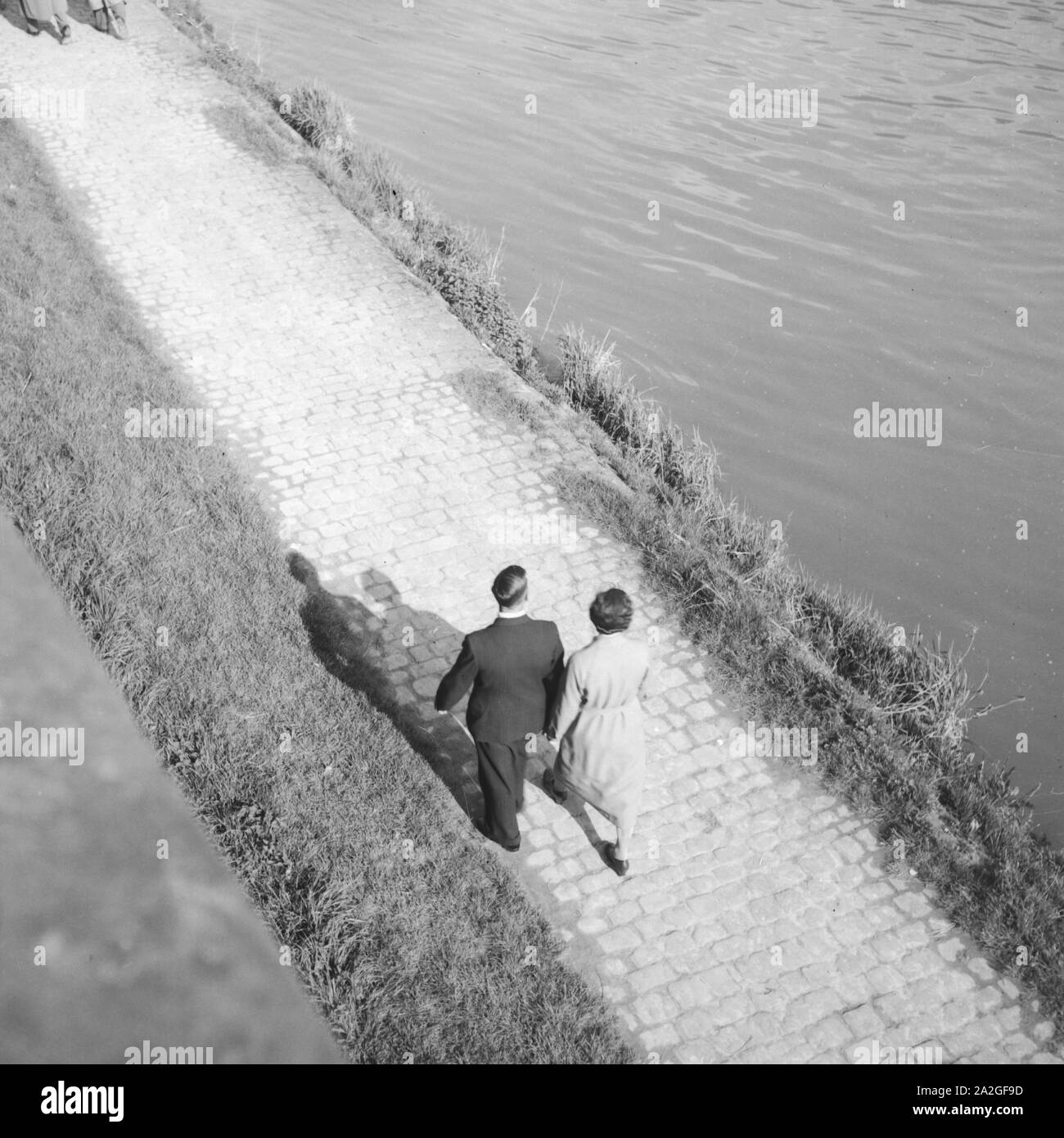 Ein Paar geht an einem Fluss spazieren, Deutschland 1930er Jahre. A couple strolling on the shore of a river, Germany 1930s. Stock Photo