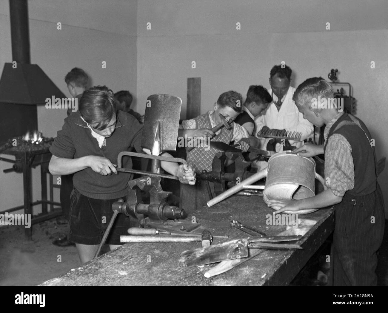 Lehrjungen im praktischen Unterricht bei der Herstellung von Spaten und Gießkannen, Deutschland 1930er Jahre. Apprentices in their practical lesson producing spades and water cans, Germany 1930s. Stock Photo