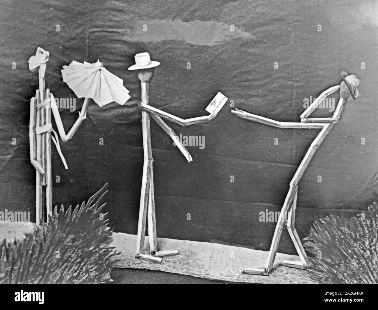 Papiermännchen-Szenerie: Streichholzmännchen gibt Feuer, Deutschland 1930er Jahre. Finger puppet scenarios: matches people lighing cigarettes, Germany 1930s. Stock Photo