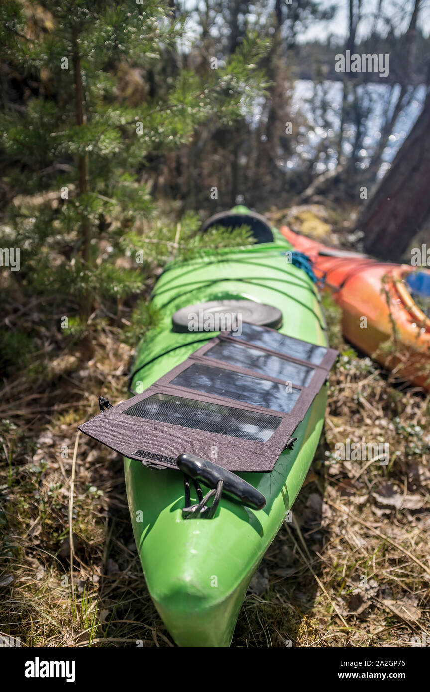 Portable solar panels lie on a green kayak in the forest and accumulate  energy Stock Photo - Alamy
