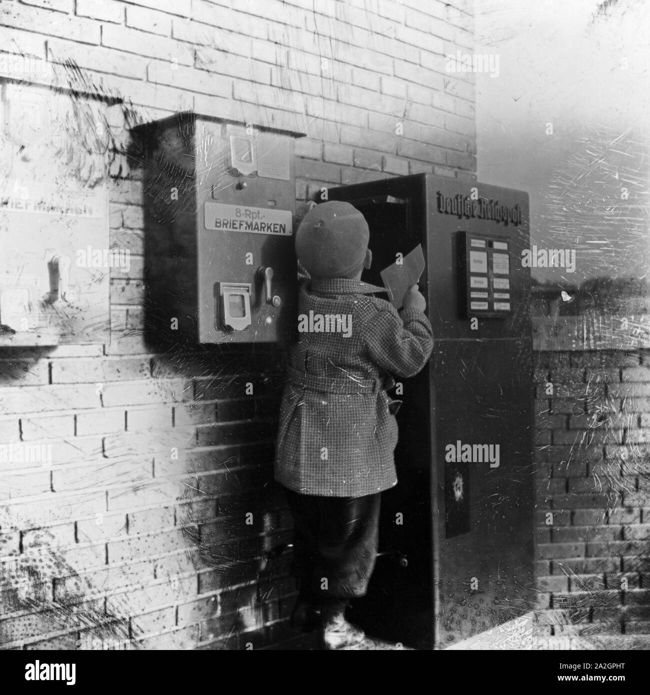 Ein kleiner Junge bringt einen Brief zum Briefkasten, Deutschland 1920er Jahre. A little boy bringing a letter to the letter box, Germany 1920s. Stock Photo