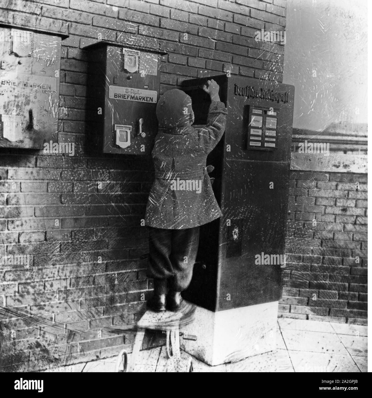 Ein kleiner Junge bringt einen Brief zum Briefkasten, Deutschland 1920er Jahre. A little boy bringing a letter to the letter box, Germany 1920s. Stock Photo