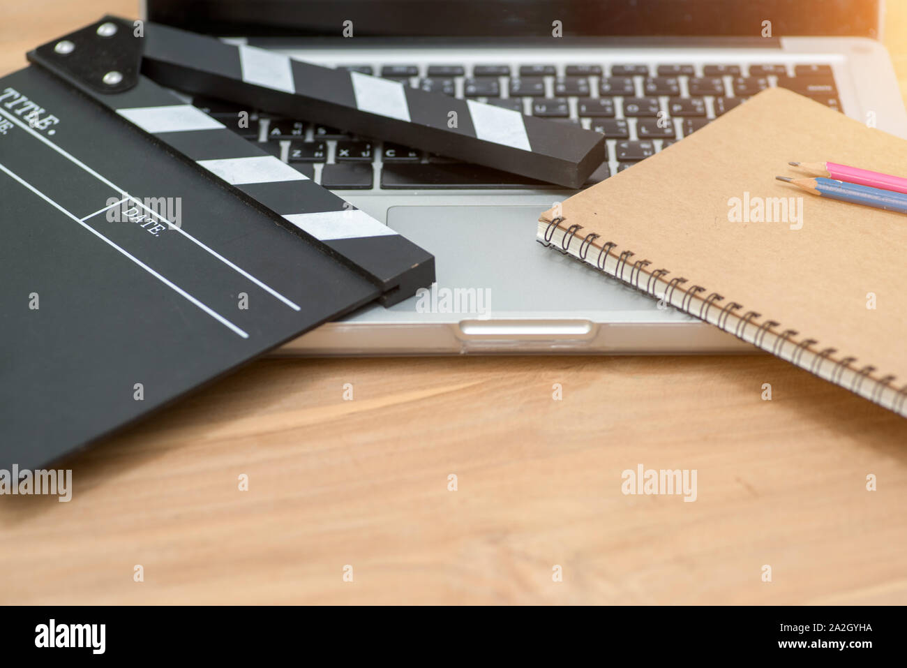 Video Editing,Movie clapper laptop and pencil notepad on the wood table top view shot.dark effect Stock Photo