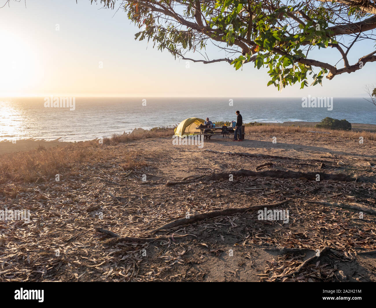Tent campsite with family on bluff over ocean at sunset in Montana de ...