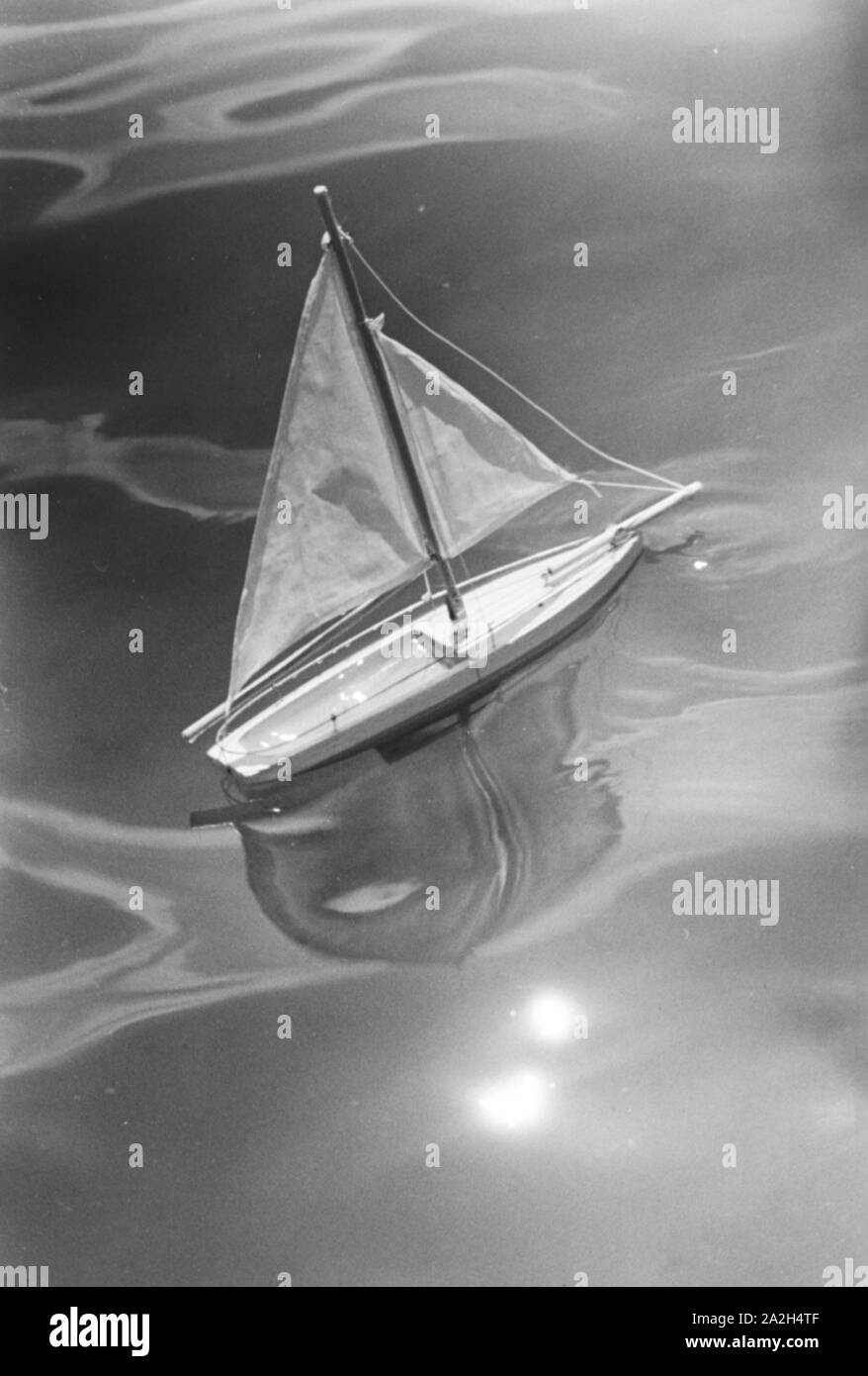 Spielzeugsegelboot im Strandbad Wannsee in Berlin, Deutschland 1930er Jahre. Toy sailing boat at lake Wannsee lido in Berlin, Germany 1930s. Stock Photo