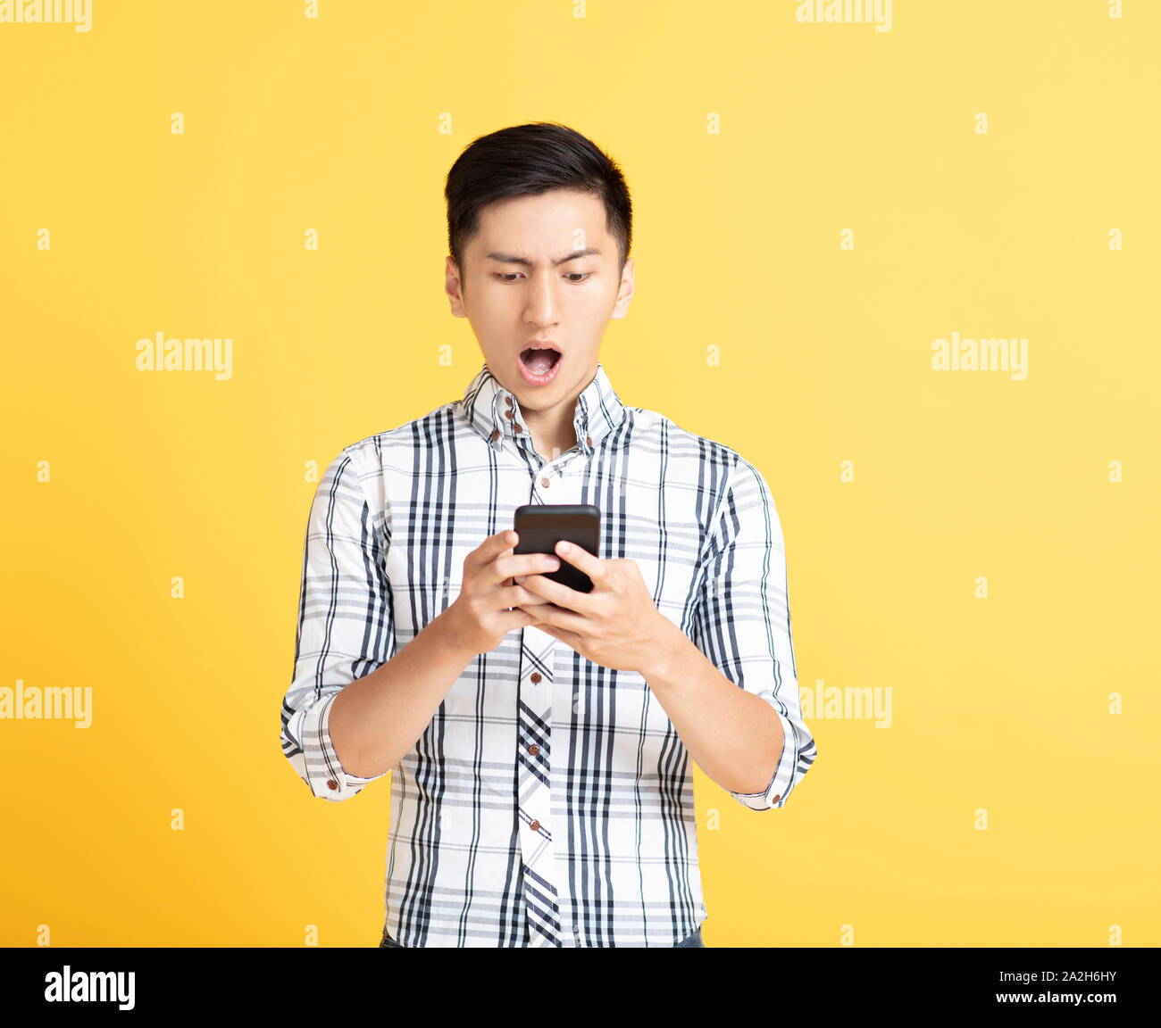 surprised young man using smart phone Stock Photo