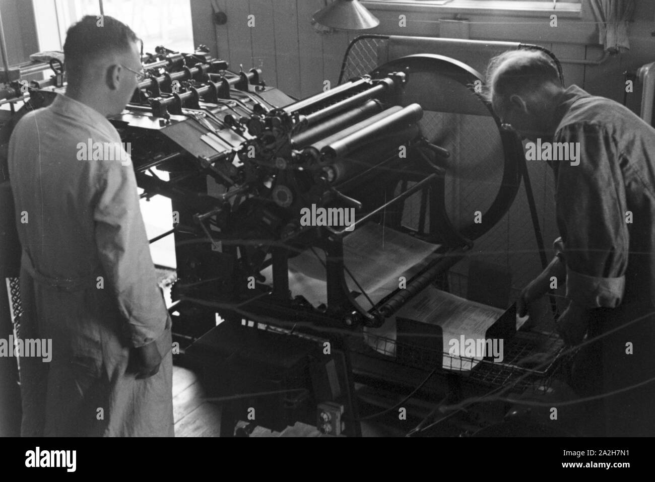 Arbeiter an einer Druckerpresse, Deutschland 1930er Jahre. Worker at a printing press, Germany 1930s. Stock Photo