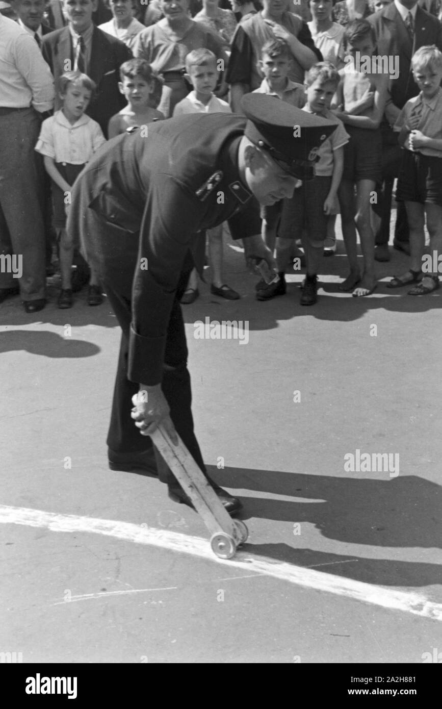 Ein Polizist streut Kalk auf eine Benzinspur bei einem Verkehrsunfall, Deutschland 1930er Jahre. A policeman strewing chalk to a petrol track at a traffic accident, Germany 1930s. Stock Photo