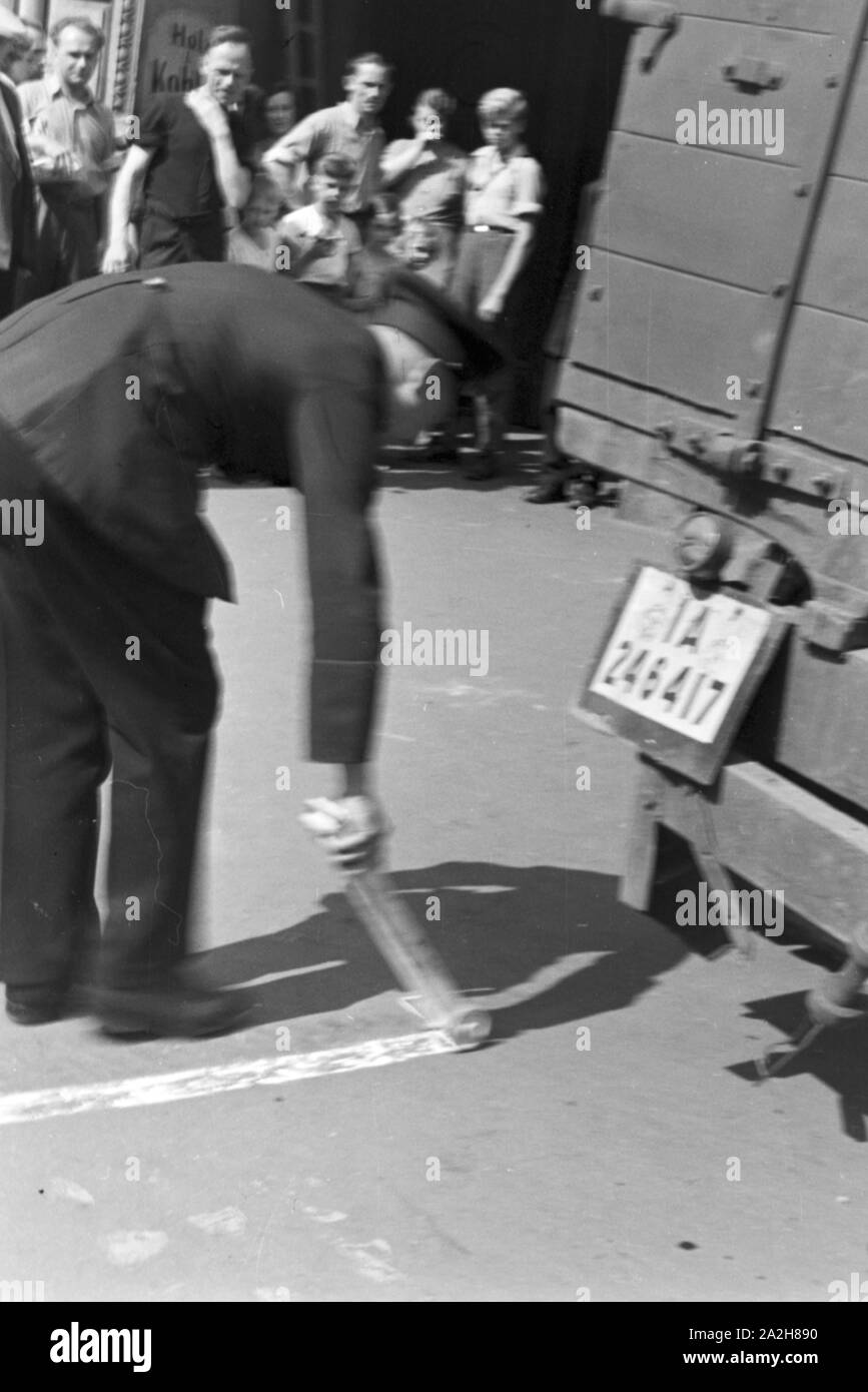 Ein Polizist streut Kalk auf eine Benzinspur bei einem Verkehrsunfall, Deutschland 1930er Jahre. A policeman strewing chalk to a petrol track at a traffic accident, Germany 1930s. Stock Photo